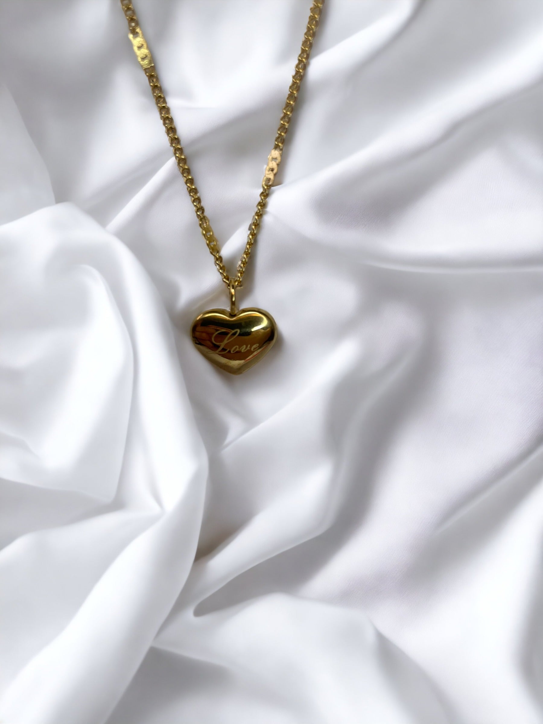Discover the essence of affection with our 'Love'  Necklace. This piece is exquisitely crafted from robust stainless steel with a gleaming gold finish, a classic that never goes out of style. The heart-shaped pendant is a universal symbol of love, and with the word 'Love' gently inscribed, it speaks directly to the heart of the wearer