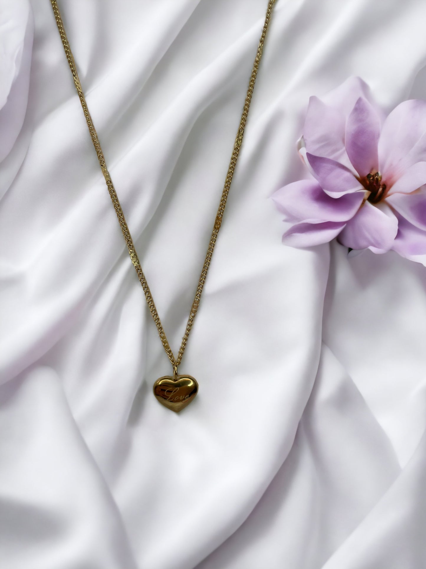 Discover the essence of affection with our 'Love'  Necklace. This piece is exquisitely crafted from robust stainless steel with a gleaming gold finish, a classic that never goes out of style. The heart-shaped pendant is a universal symbol of love, and with the word 'Love' gently inscribed, it speaks directly to the heart of the wearer