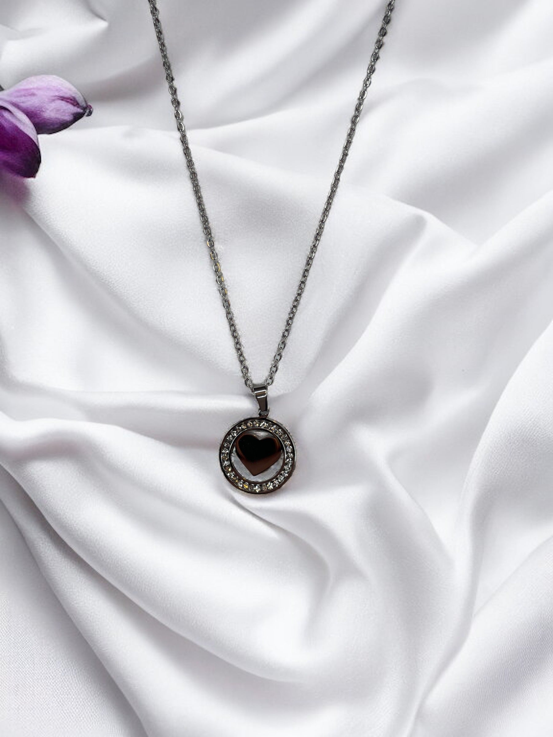 Presenting our Sparkle Heart Necklace – where elegance meets timeless charm. This necklace features a stainless steel composition with a luxurious gold finish, offering enduring beauty and resilience. At its center is a captivating heart, encased within a circle of shimmering cubic zirconia stones that catch the light with every movement. 