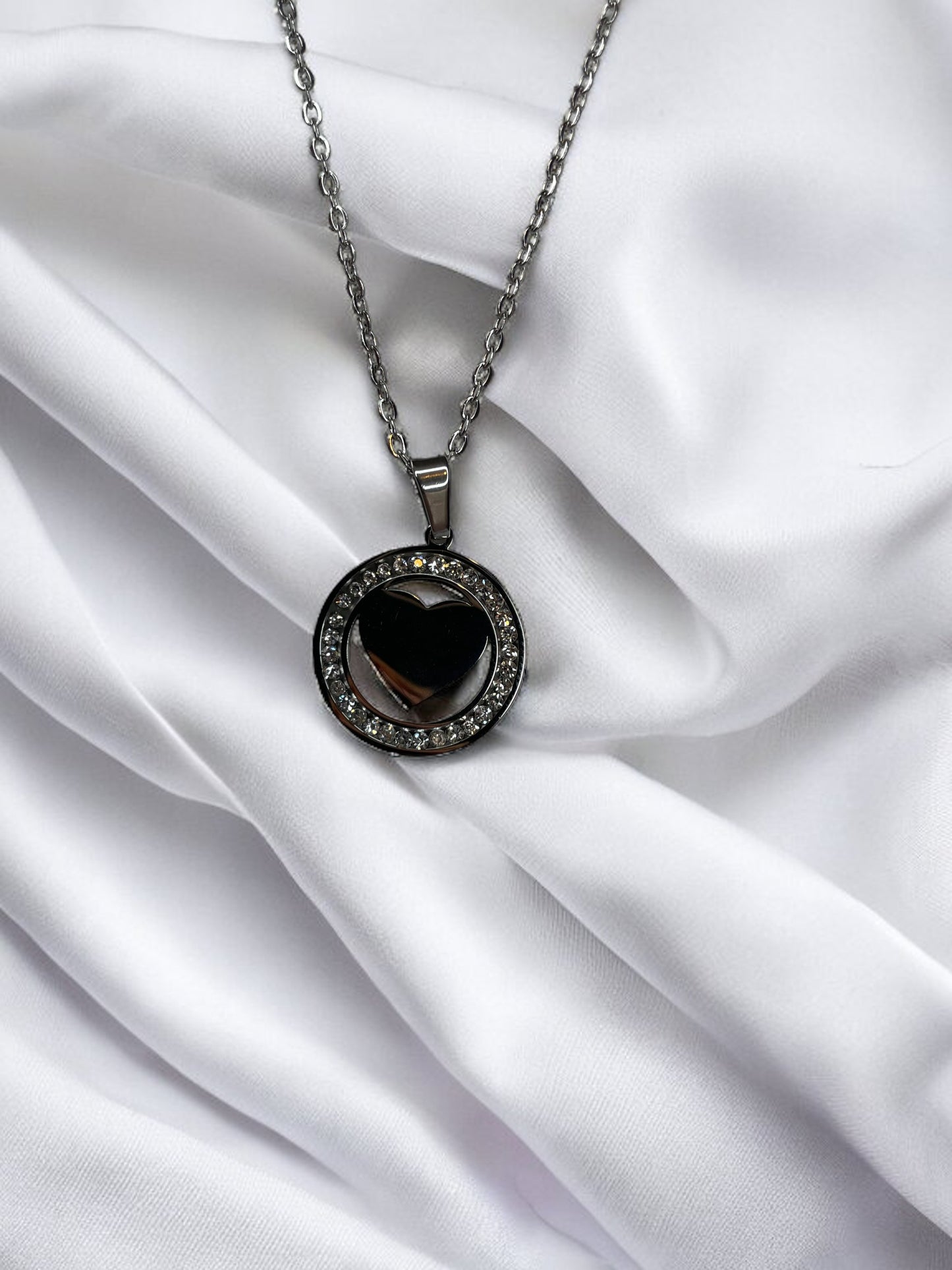 Presenting our Sparkle Heart Necklace – where elegance meets timeless charm. This necklace features a stainless steel composition with a luxurious gold finish, offering enduring beauty and resilience. At its center is a captivating heart, encased within a circle of shimmering cubic zirconia stones that catch the light with every movement. 