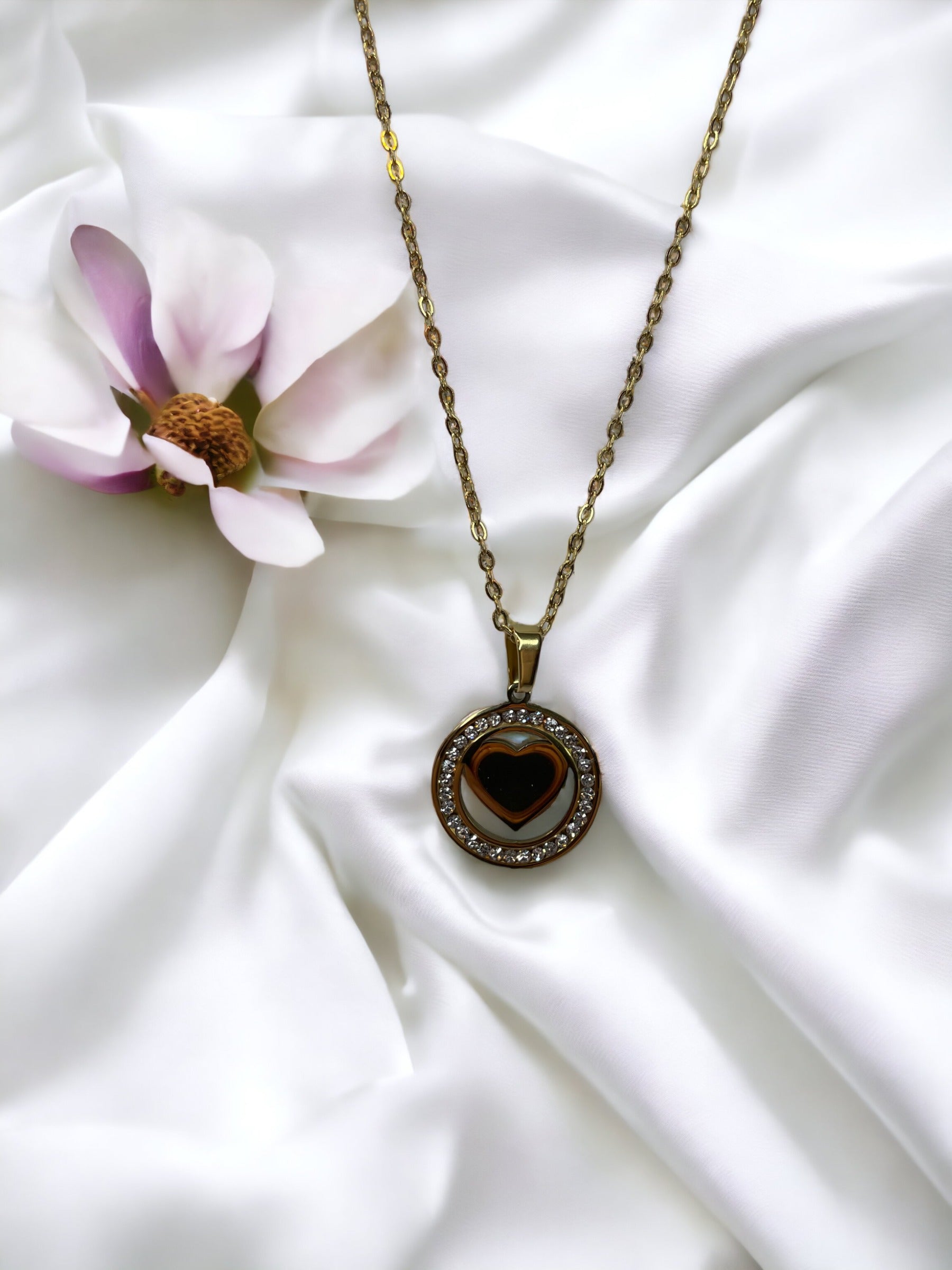 Presenting our Sparkle Heart Necklace – where elegance meets timeless charm. This necklace features a stainless steel composition with a luxurious gold finish, offering enduring beauty and resilience. At its center is a captivating heart, encased within a circle of shimmering cubic zirconia stones that catch the light with every movement. 