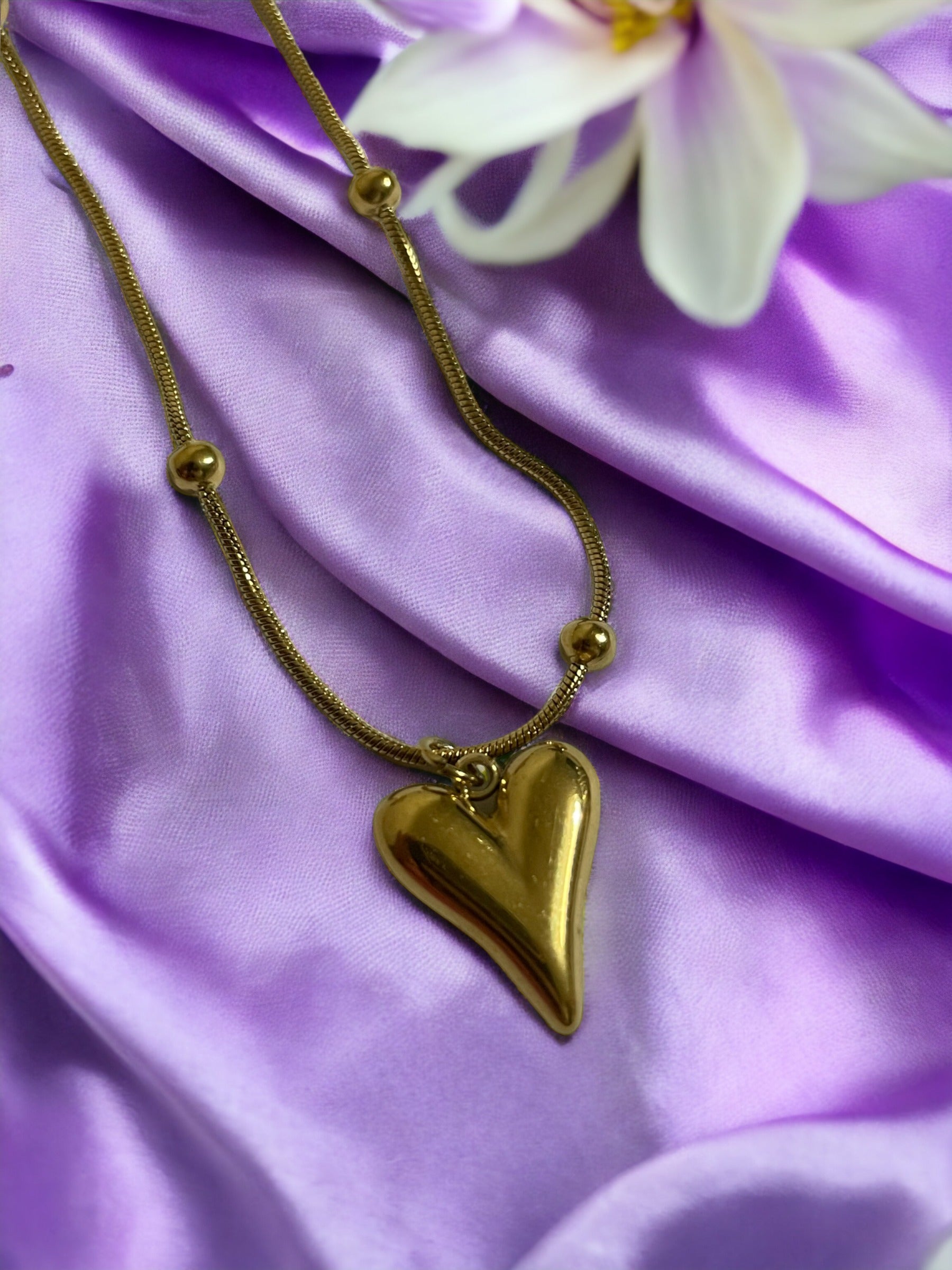Introducing our Golden Heart Necklace – a modern twist on classic love. This exquisite piece is fashioned from premium stainless steel with a gleaming gold finish, offering both durability and a touch of sophistication. The heart-shaped pendant is polished to a mirror shine, hanging gracefully from a delicate chain adorned with spherical accents. 