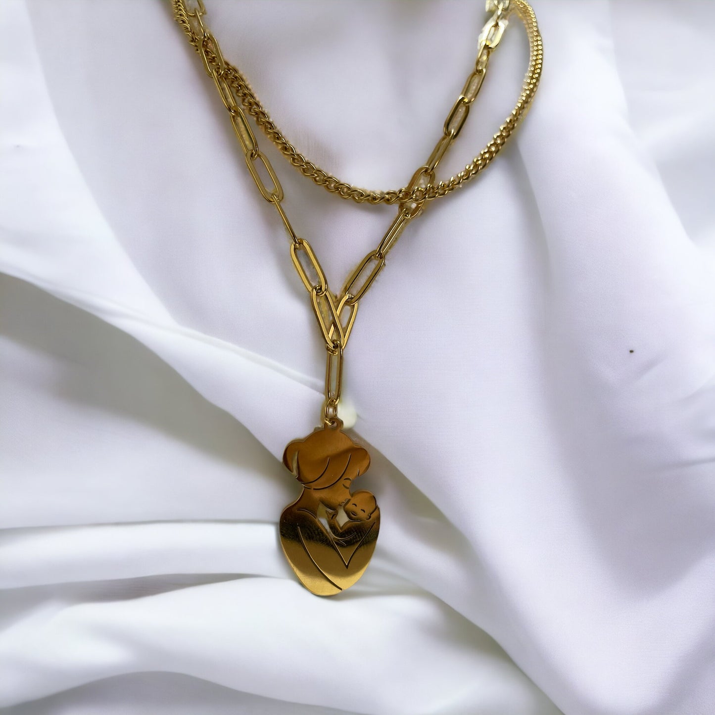 The Maternal Grace Pendant Necklace features a sophisticated design with a mother and her baby in a gentle embrace, forming an abstract heart shape within the pendant. Depending on your selection, the pendant comes in the resilient sheen of stainless steel or the timeless elegance of gold plating. The accompanying chain is tastefully designed to complement the pendant, making the necklace a graceful statement of motherly love and tenderness.
