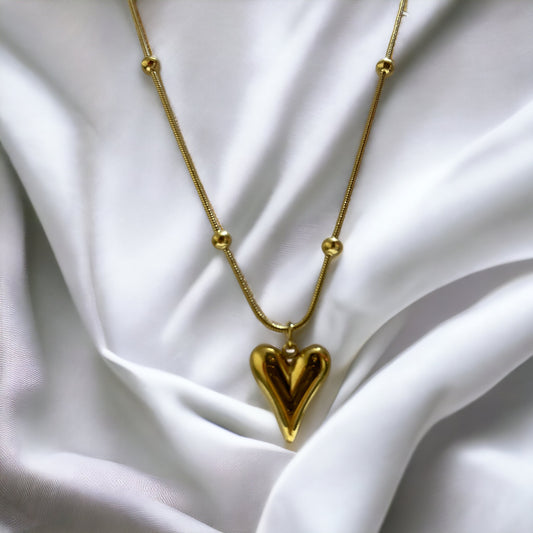 Introducing our Golden Heart Necklace – a modern twist on classic love. This exquisite piece is fashioned from premium stainless steel with a gleaming gold finish, offering both durability and a touch of sophistication. The heart-shaped pendant is polished to a mirror shine, hanging gracefully from a delicate chain adorned with spherical accents.