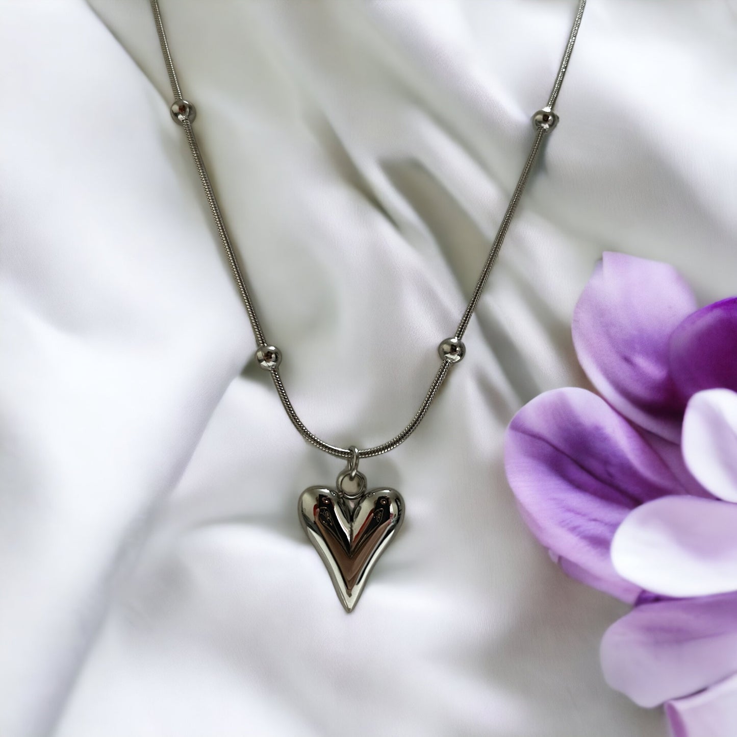 Introducing our Golden Heart Necklace – a modern twist on classic love. This exquisite piece is fashioned from premium stainless steel with a gleaming gold finish, offering both durability and a touch of sophistication. The heart-shaped pendant is polished to a mirror shine, hanging gracefully from a delicate chain adorned with spherical accents.