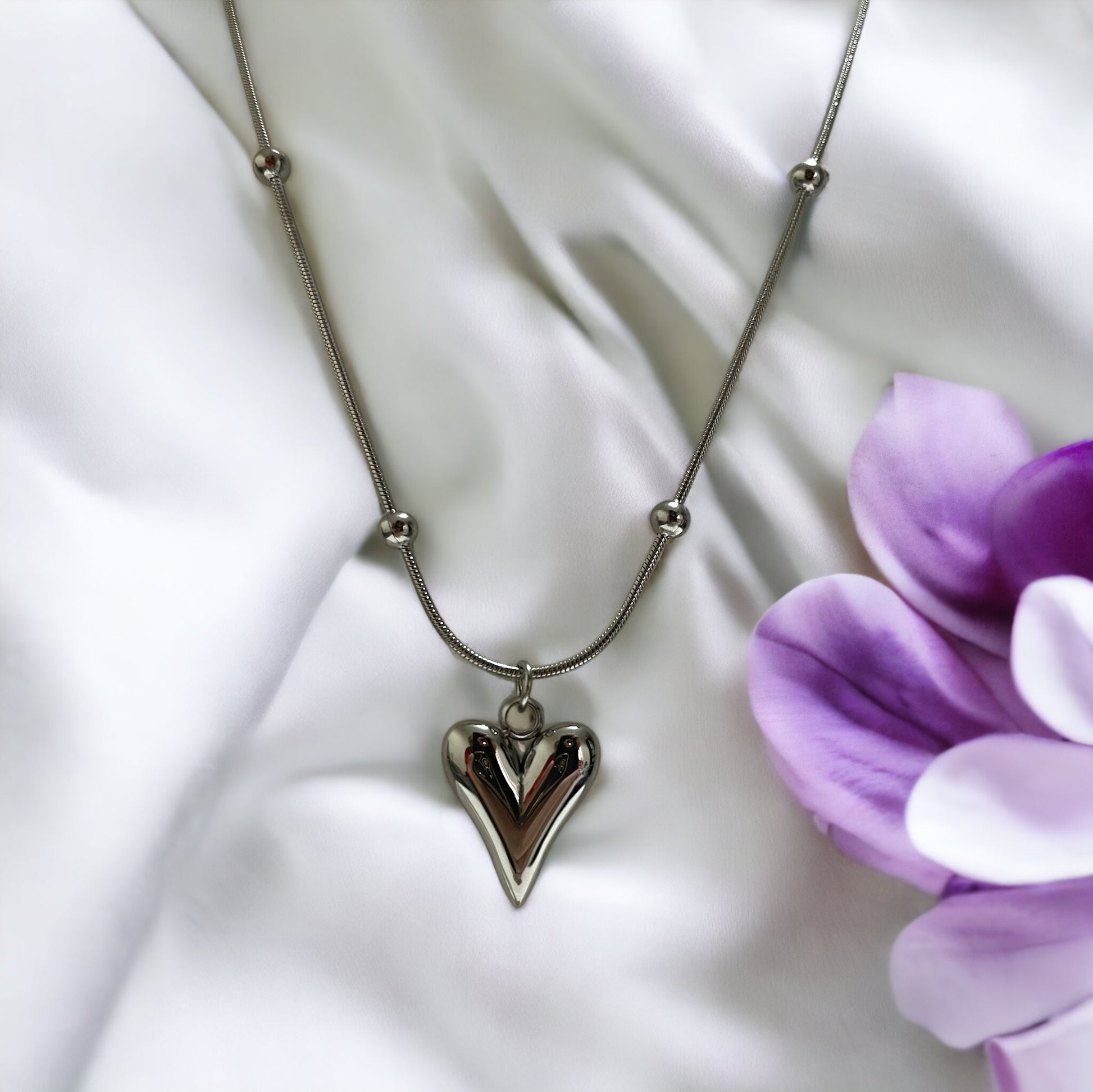 Introducing our Golden Heart Necklace – a modern twist on classic love. This exquisite piece is fashioned from premium stainless steel with a gleaming gold finish, offering both durability and a touch of sophistication. The heart-shaped pendant is polished to a mirror shine, hanging gracefully from a delicate chain adorned with spherical accents.