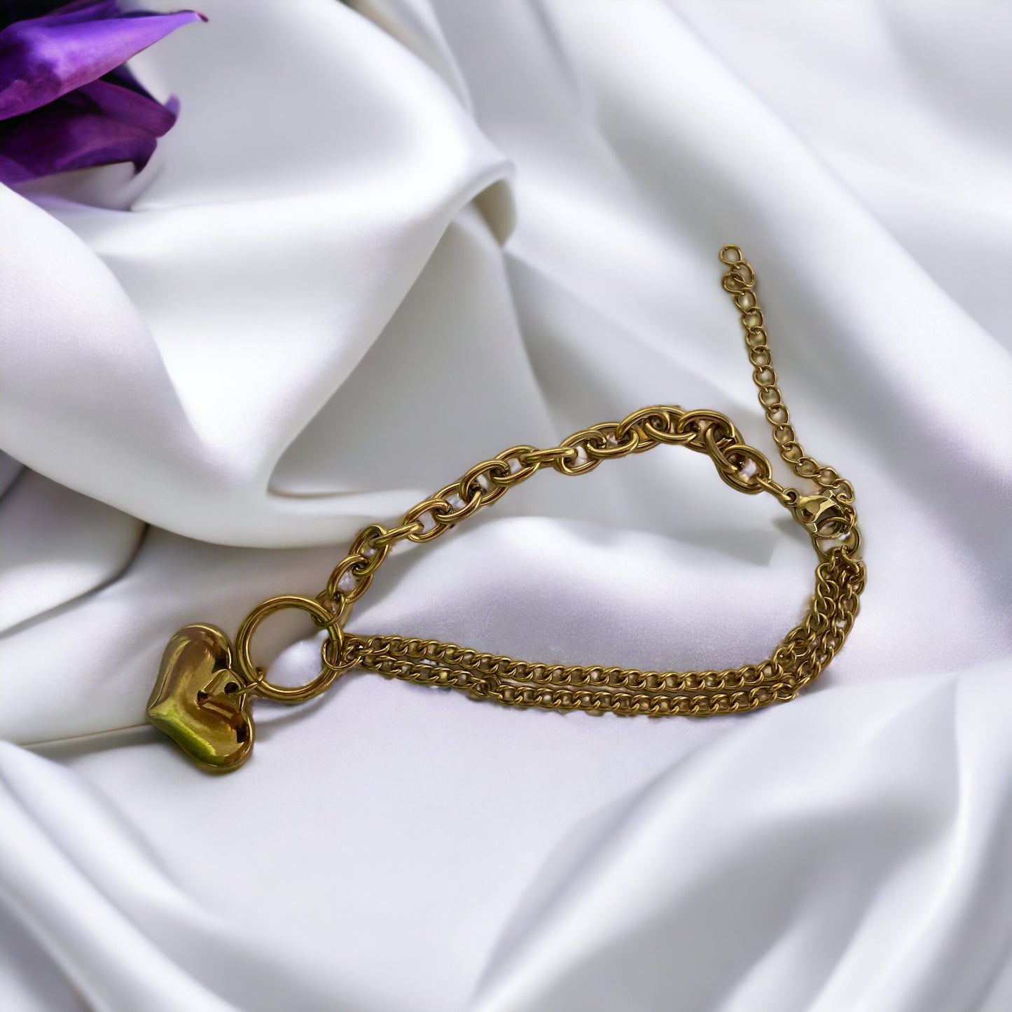 The heart charm adds a romantic and personal touch, making it a standout accessory that symbolizes love and warmth. This bracelet is also available in a stainless steel finish, offering a sleek and modern alternative to the classic gold, ensuring durability and a lasting sheen. It's a versatile piece that can be worn alone for a subtle statement or layered with other bracelets for a more personalized look.