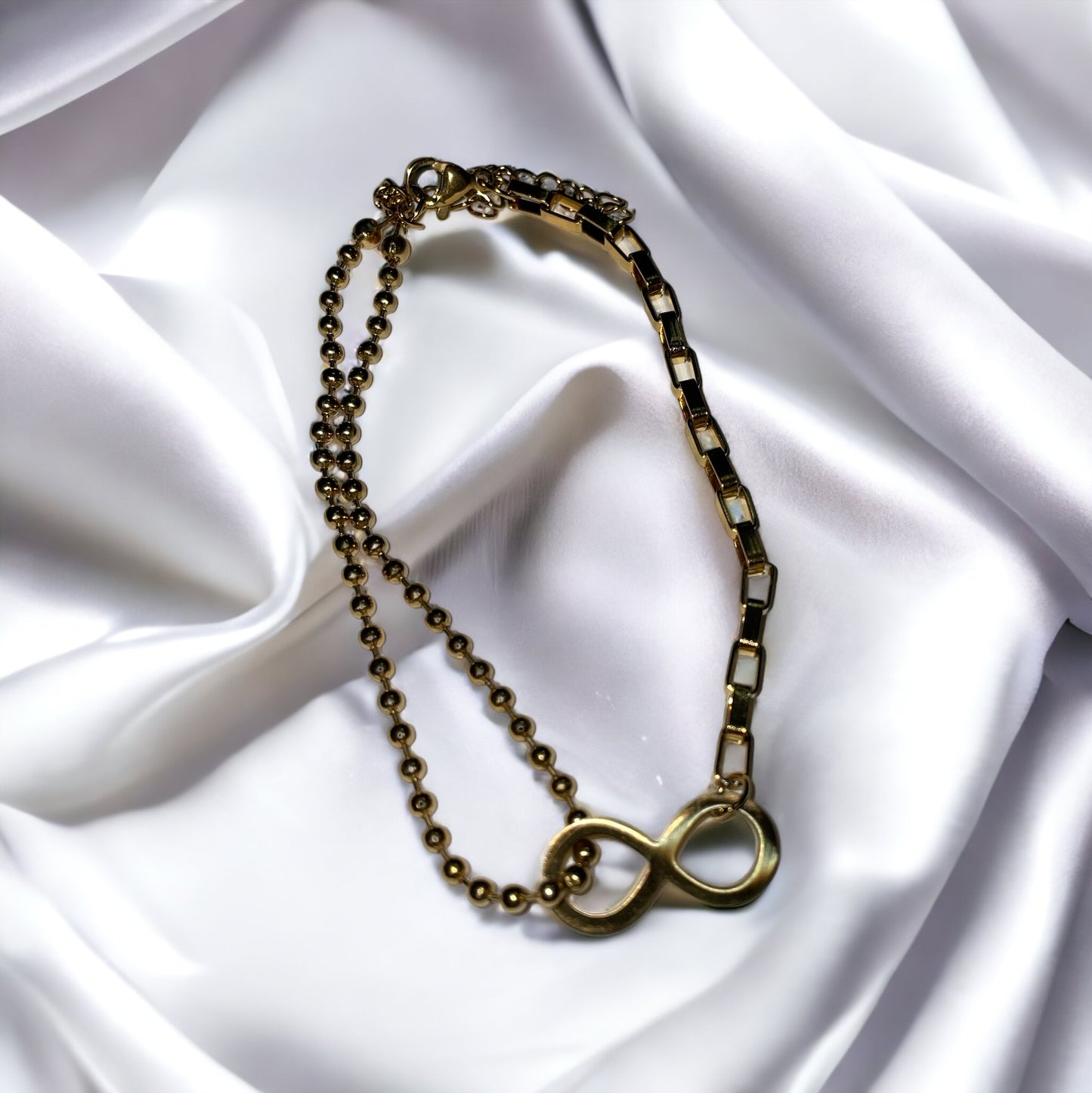 The bracelet seamlessly blends spherical beads with sleek, rectangular links, creating a harmonious balance of shapes and textures. Its gold-plated finish gives it a warm, inviting glow, capturing the eye and symbolizing a connection that lasts forever. This bracelet is also available in a stainless steel variant, offering durability along with its timeless elegance.