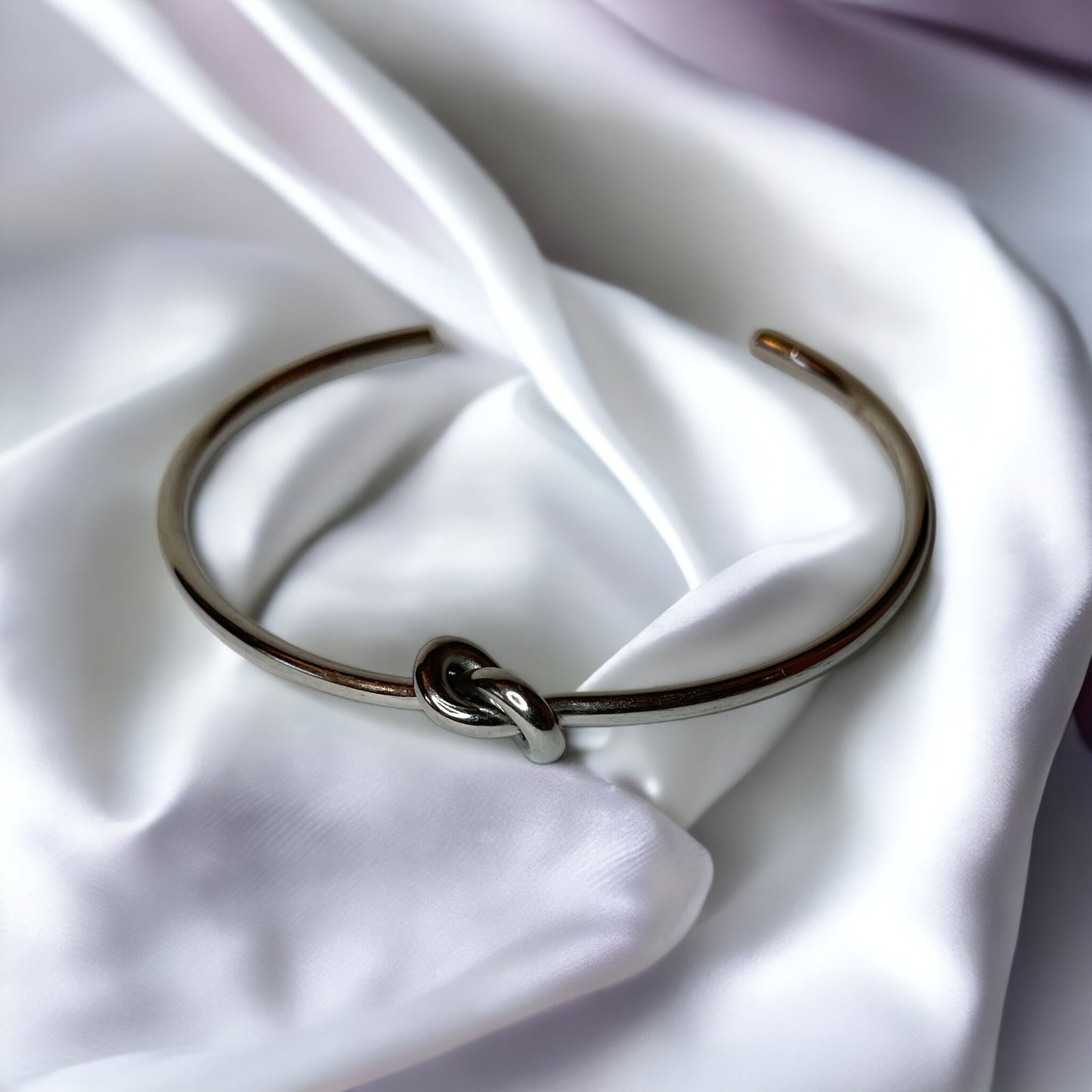 Infinite Embrace Bracelet is a sophisticated accessory designed to symbolize the unending strength of love and connection. It is adjustable in size and can comfortably fit most wrists.The bracelet's most distinctive feature is its clasp, which consists of two parts that interlock in a seamless fashion. The design resembles an infinite loop, reflecting a timeless bond or relationship.