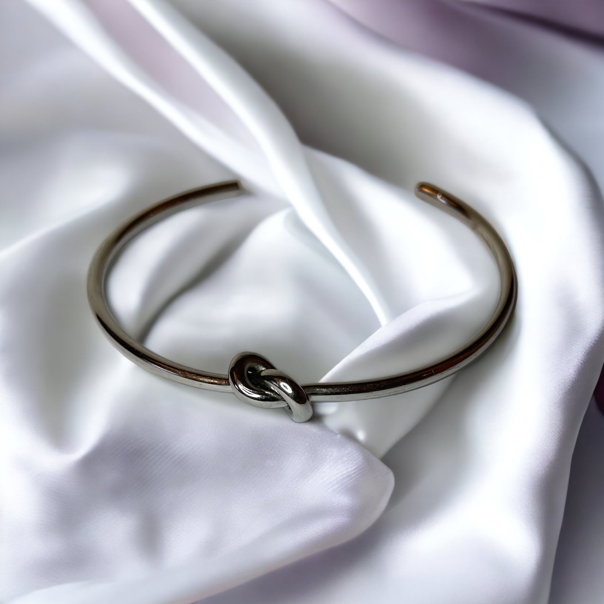 Infinite Embrace Bracelet is a sophisticated accessory designed to symbolize the unending strength of love and connection. It is adjustable in size and can comfortably fit most wrists.The bracelet's most distinctive feature is its clasp, which consists of two parts that interlock in a seamless fashion. The design resembles an infinite loop, reflecting a timeless bond or relationship.