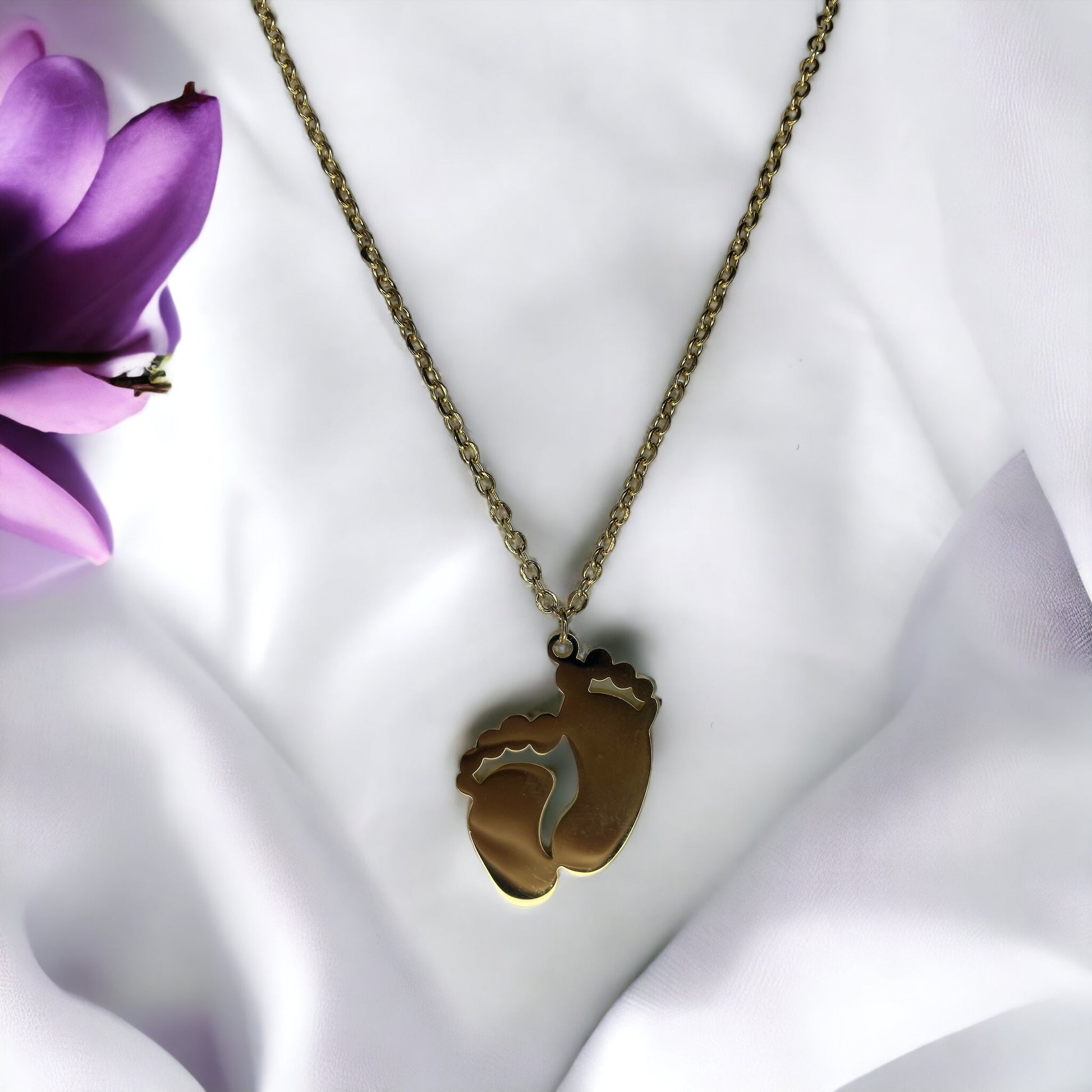 This image displays a charming necklace featuring a pendant shaped like a small child's footprint, signifying beginnings and growth. It has a polished finish with a choice between the classic sheen of stainless steel and the warm glow of gold plating. The pendant hangs gracefully on a matching chain, making it an ideal piece for everyday wear or as a sentimental gift to commemorate life's precious moments."